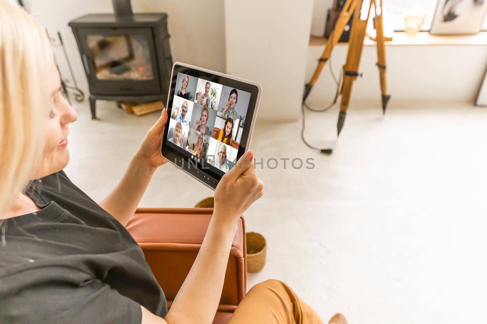 Photo of a young woman sitting by the window and using digital tablet at home