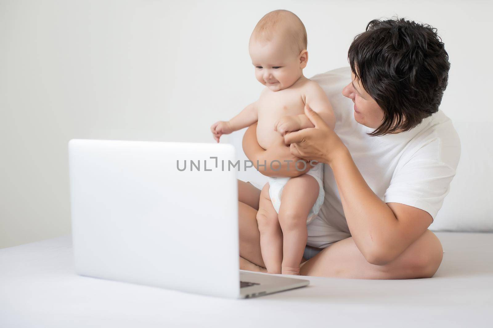 Mom and baby looking at a laptop and smiling happy. by Andelov13