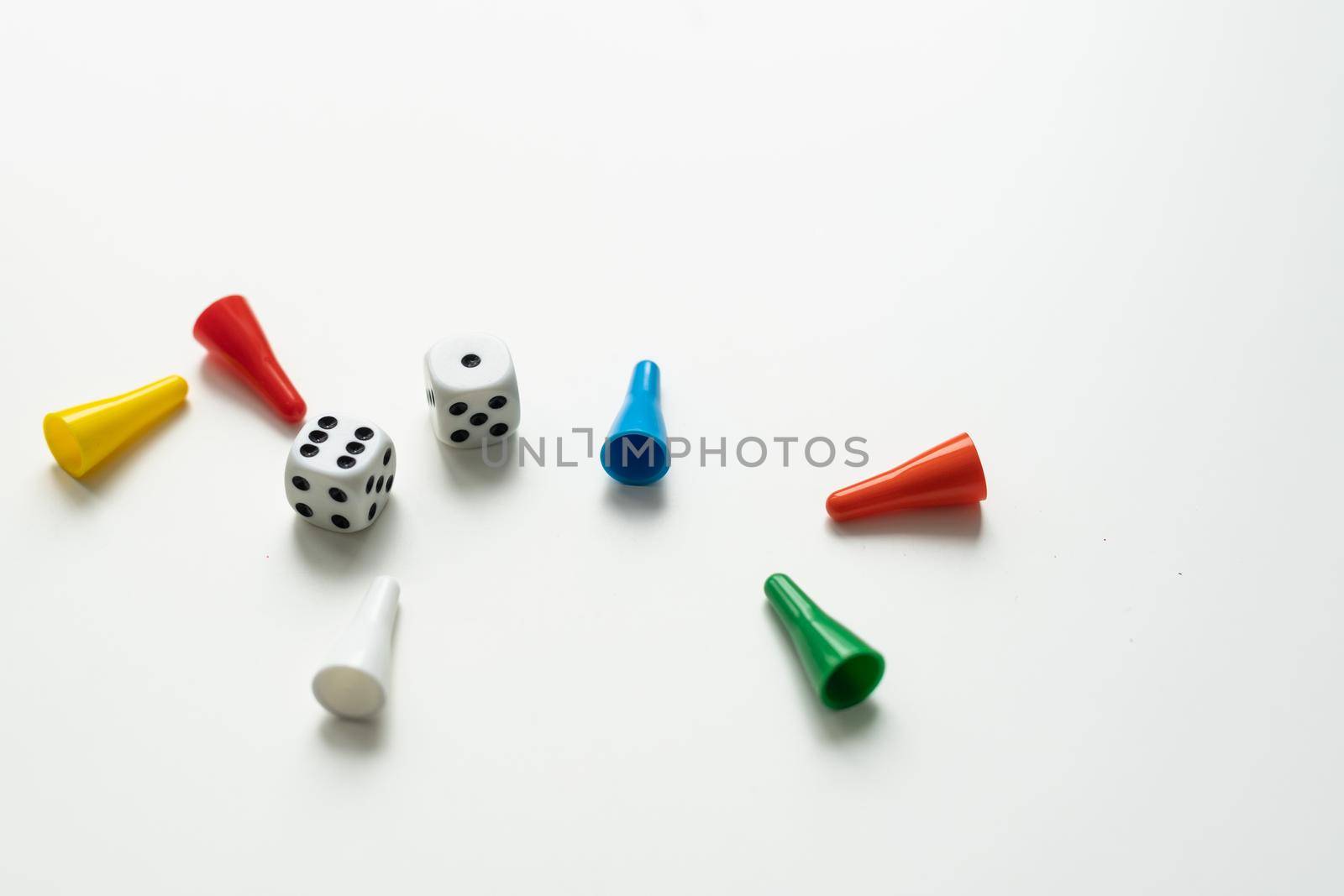 Multi-colored playing chips and dice cubes are grouped together on a white background: the concept of Board games, entertainment, background, games at home for the whole family.