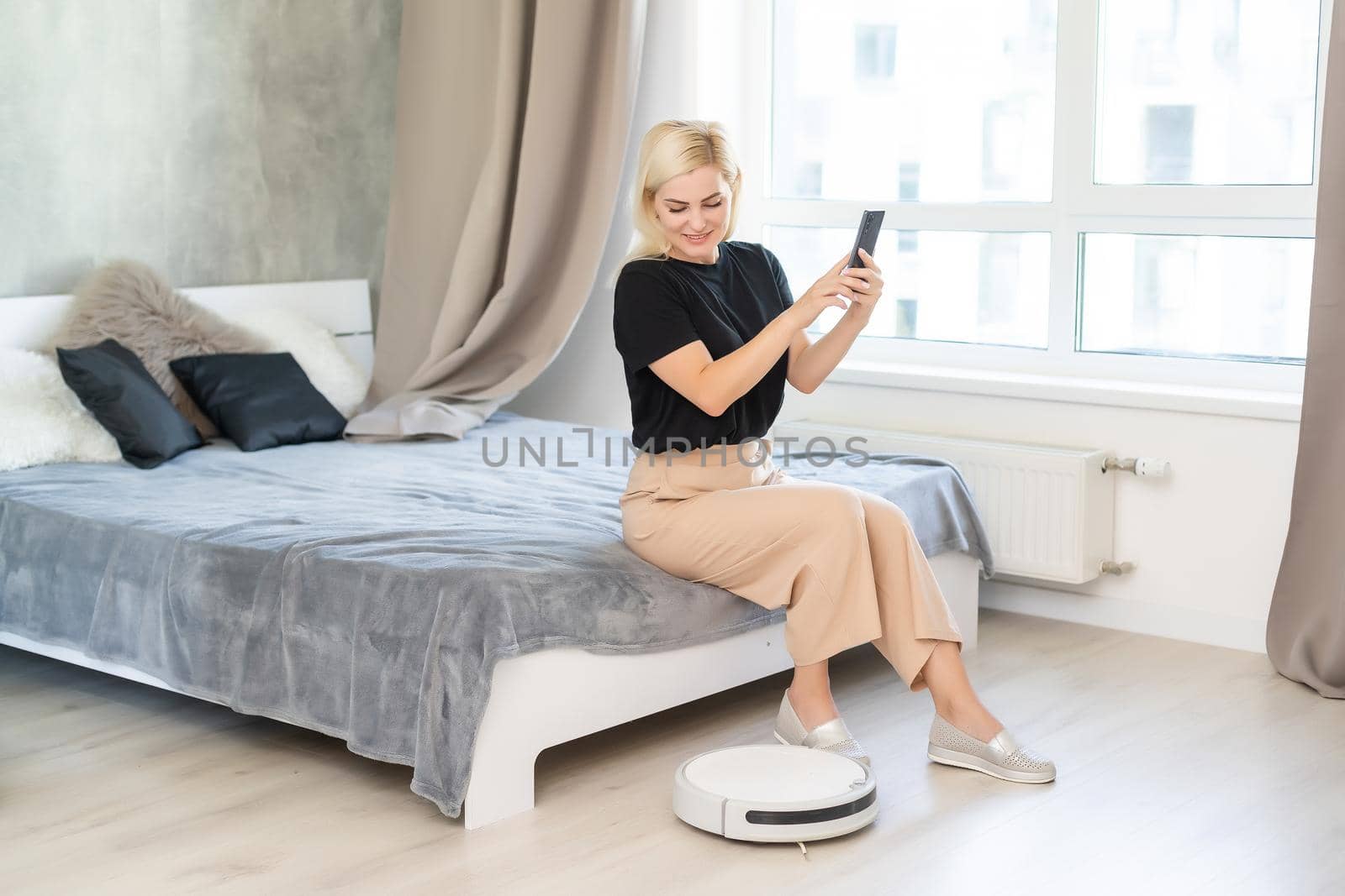 people, housework and technology concept - happy woman with tablet pc computer and robot vacuum cleaner at home.