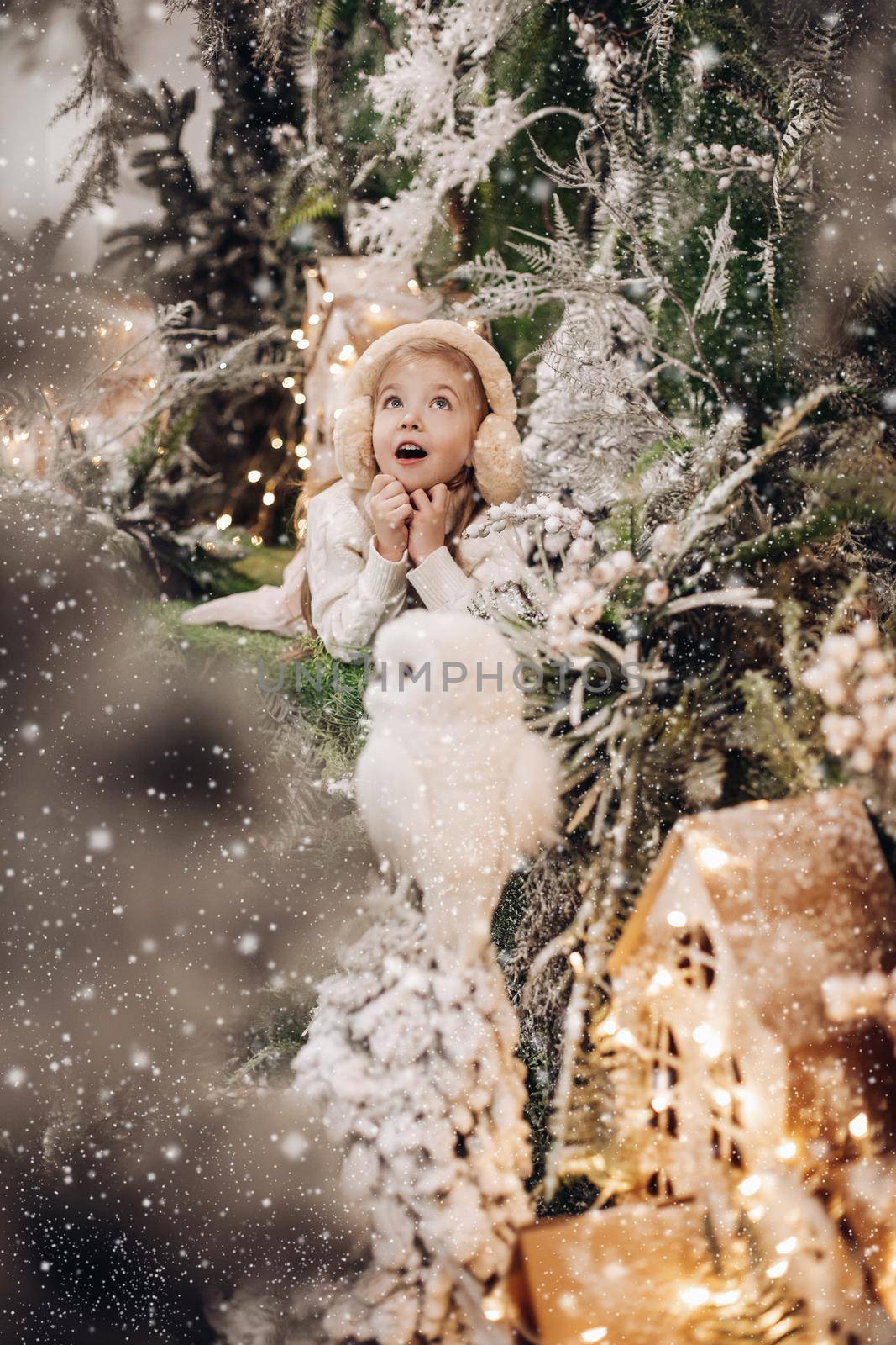 picture of wondered little girl in light clothes lies on a christmas decoration with trees and a little white owl by StudioLucky