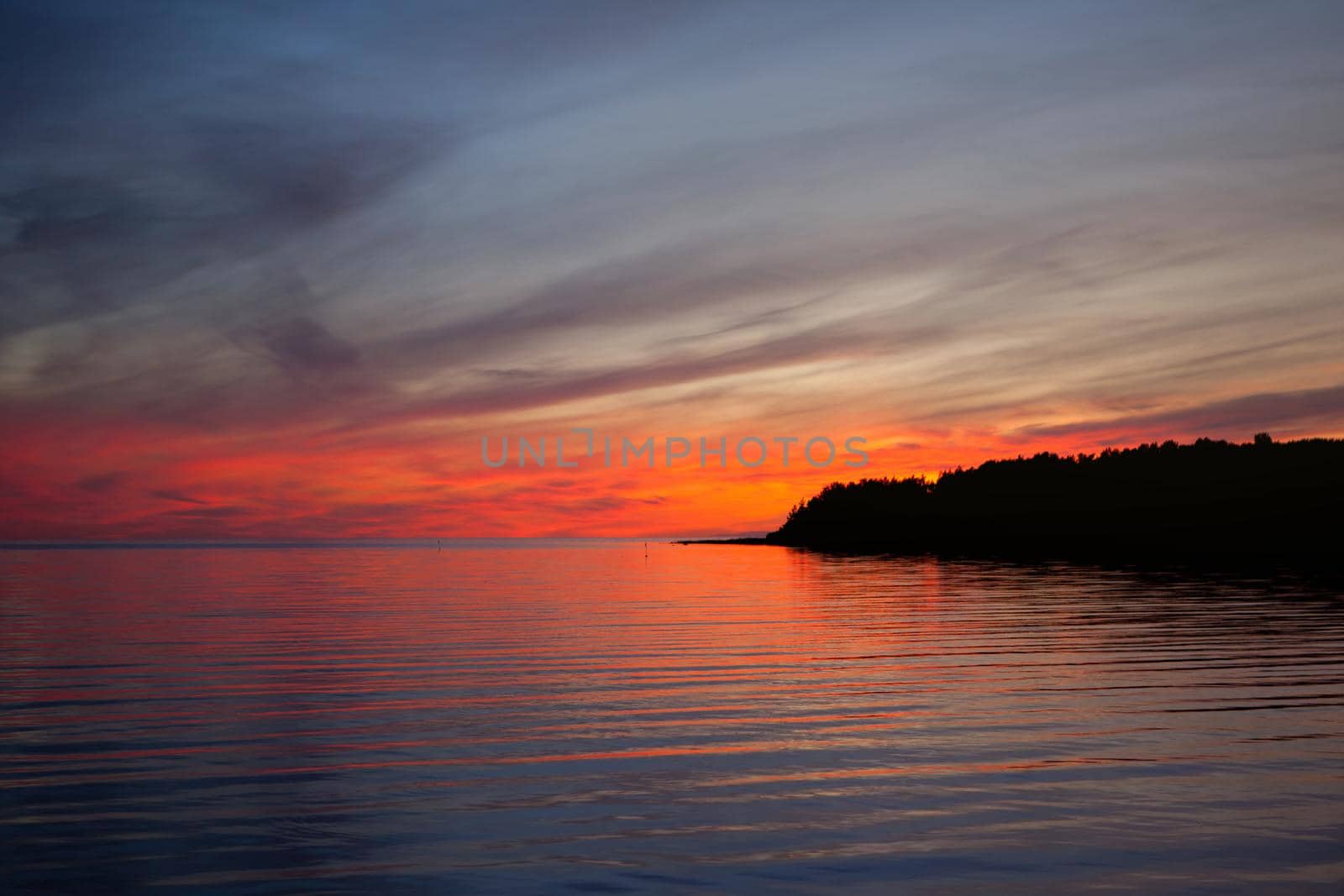 red and blue sunset on the sea - burning dramatic sky at evening in baltic sea by julija
