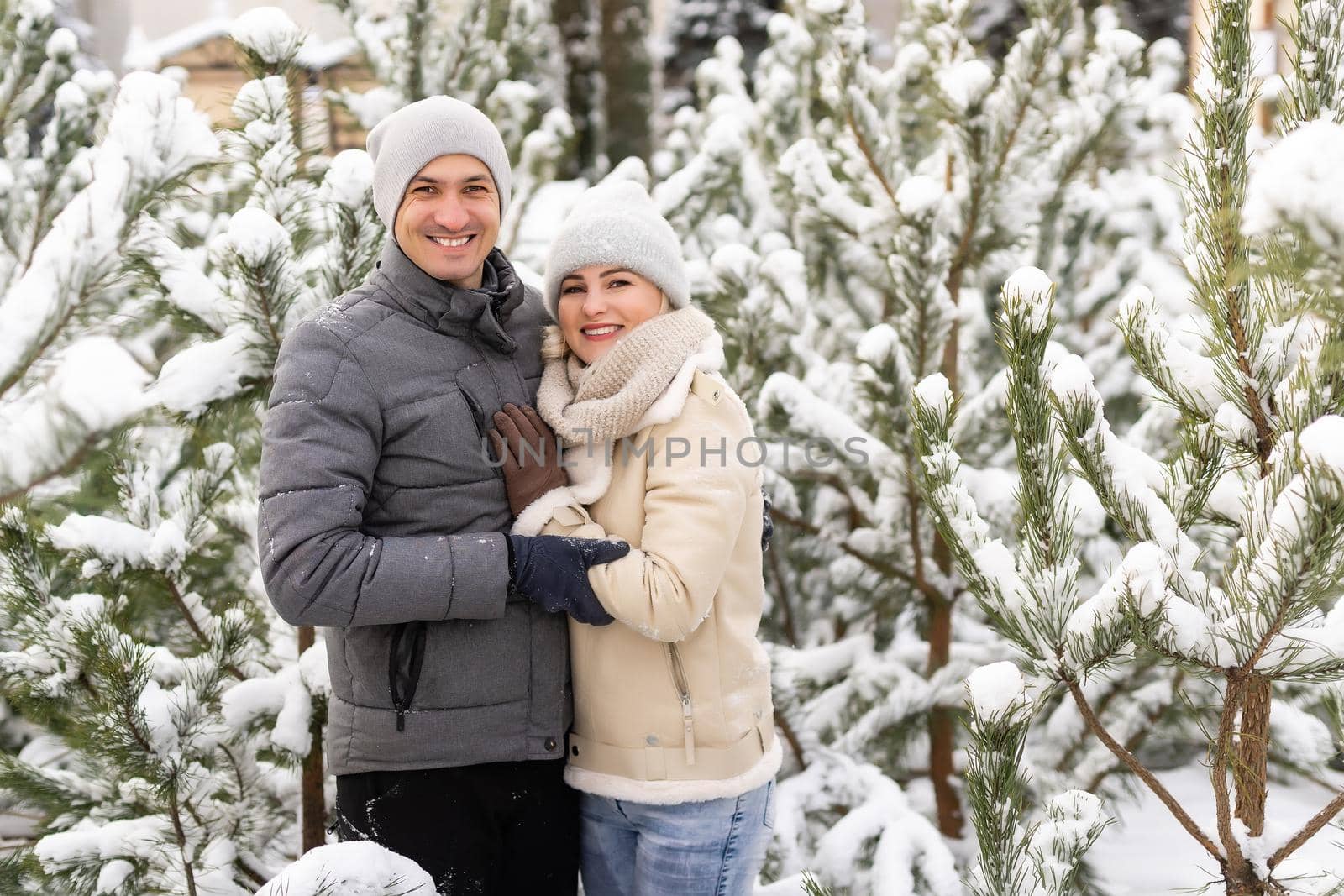 happy loving couple walking in snowy winter forest, spending christmas vacation together. Outdoor seasonal activities. Lifestyle capture.