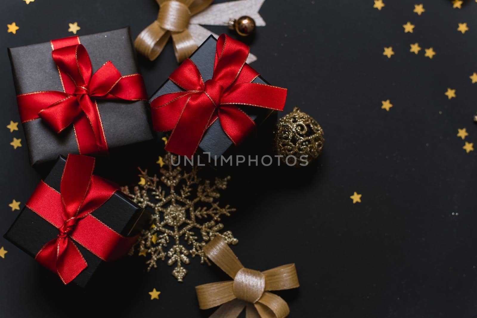 Beautiful Christmas golden snowflakes with gifts on a dark black background. Flat lay. Copy space