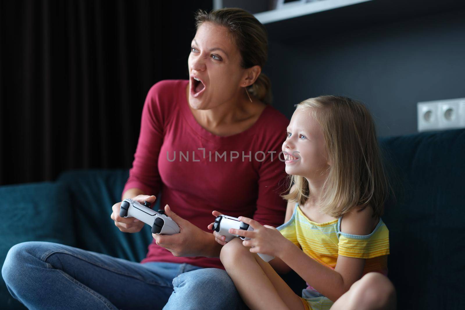 Mom and daughter are playing video games at home by kuprevich