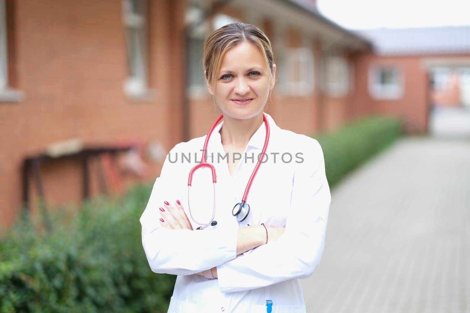 A woman doctor stands on the street near the clinic, close-up, blurry. Rehabilitation center, buildings for the isolation of viral patients