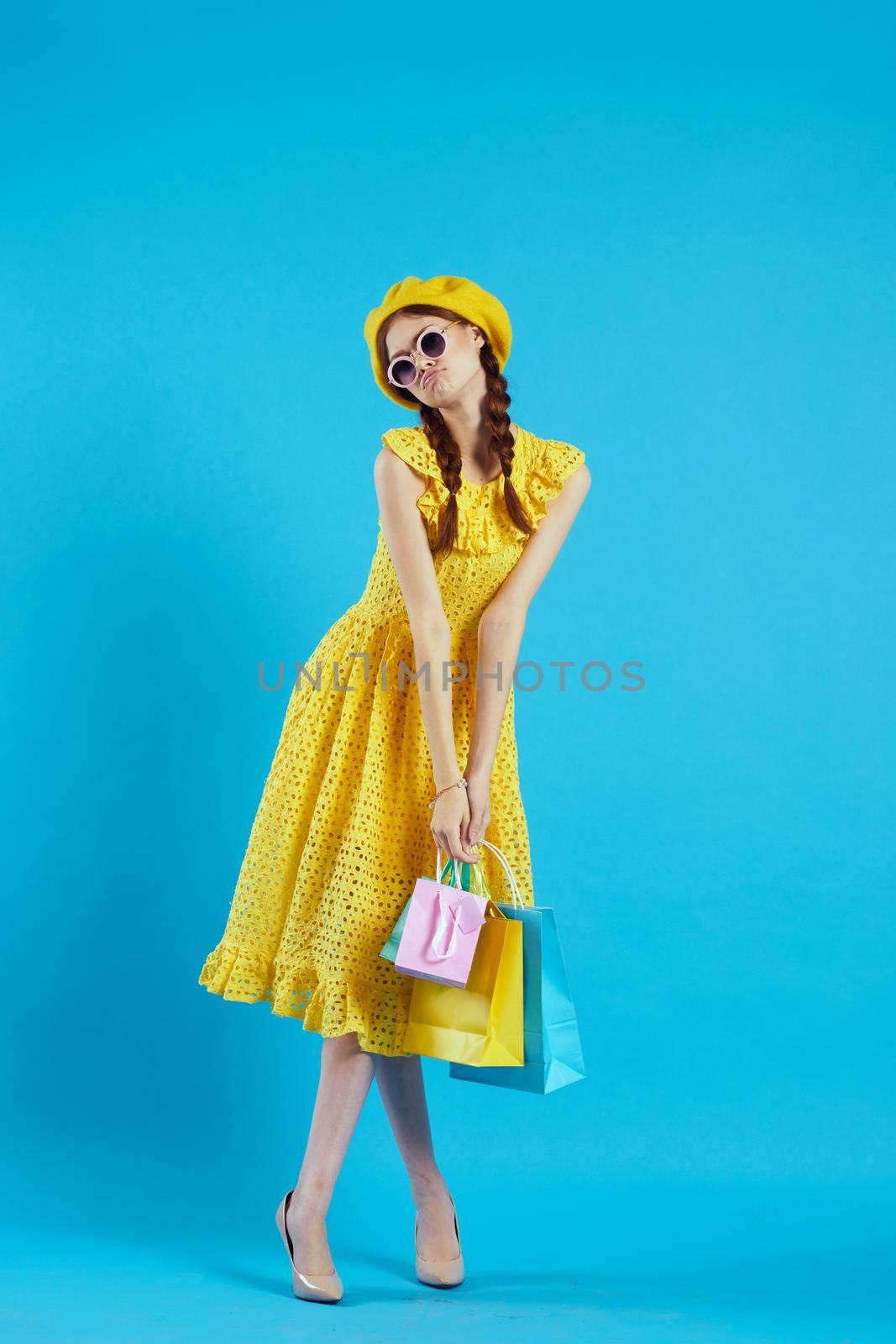 smiling woman yellow dress shopping fun blue background. High quality photo