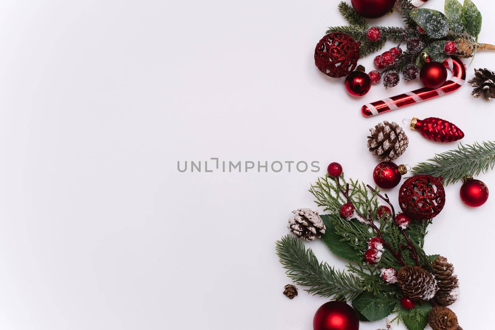 Christmas photo of branches of a tree with red toys and balls on a white background.