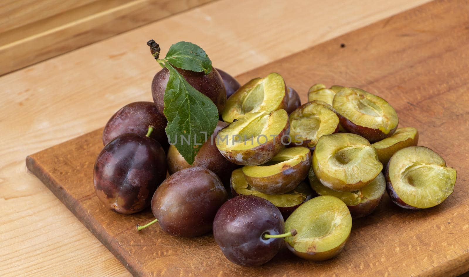 Fresh juicy plums on a wooden background by Mindru