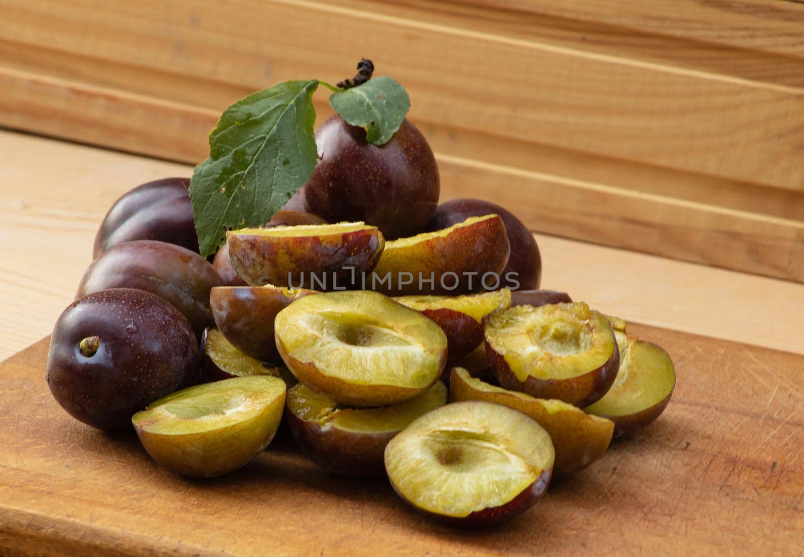 Fresh juicy plums on a wooden background by Mindru