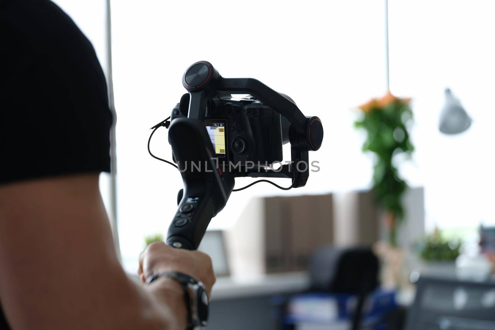 Male photographer with steadicam and camera, close-up, blurry. Professional equipment for photo and video filming, operator