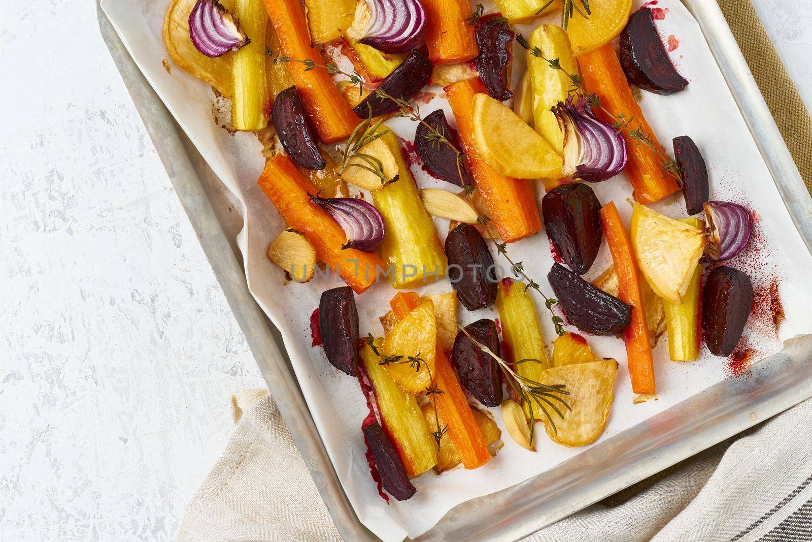 Colorful roasted vegetables on tray with parchment. Mix of carrots, beets, turnips by NataBene