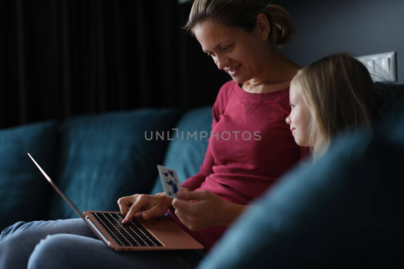 A woman with a child on the couch pays for online purchases, close-up. Online grocery ordering during a pandemic