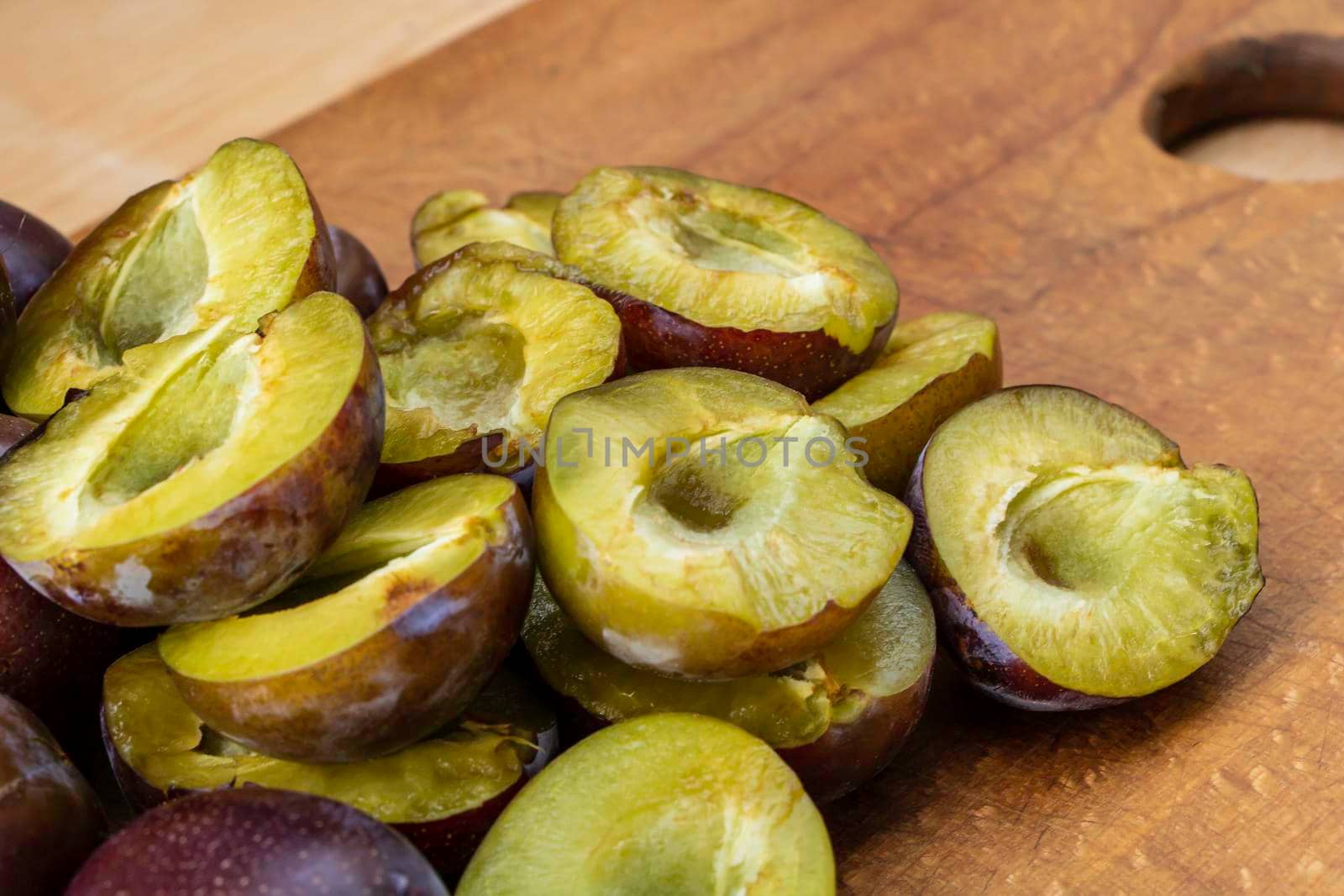 Sliced tasty juicy plums on wooden background.