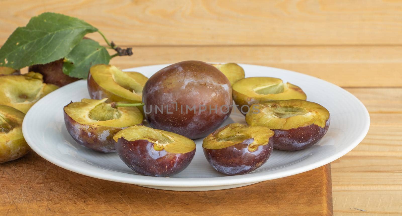 Fresh juicy plums on a wooden background by Mindru