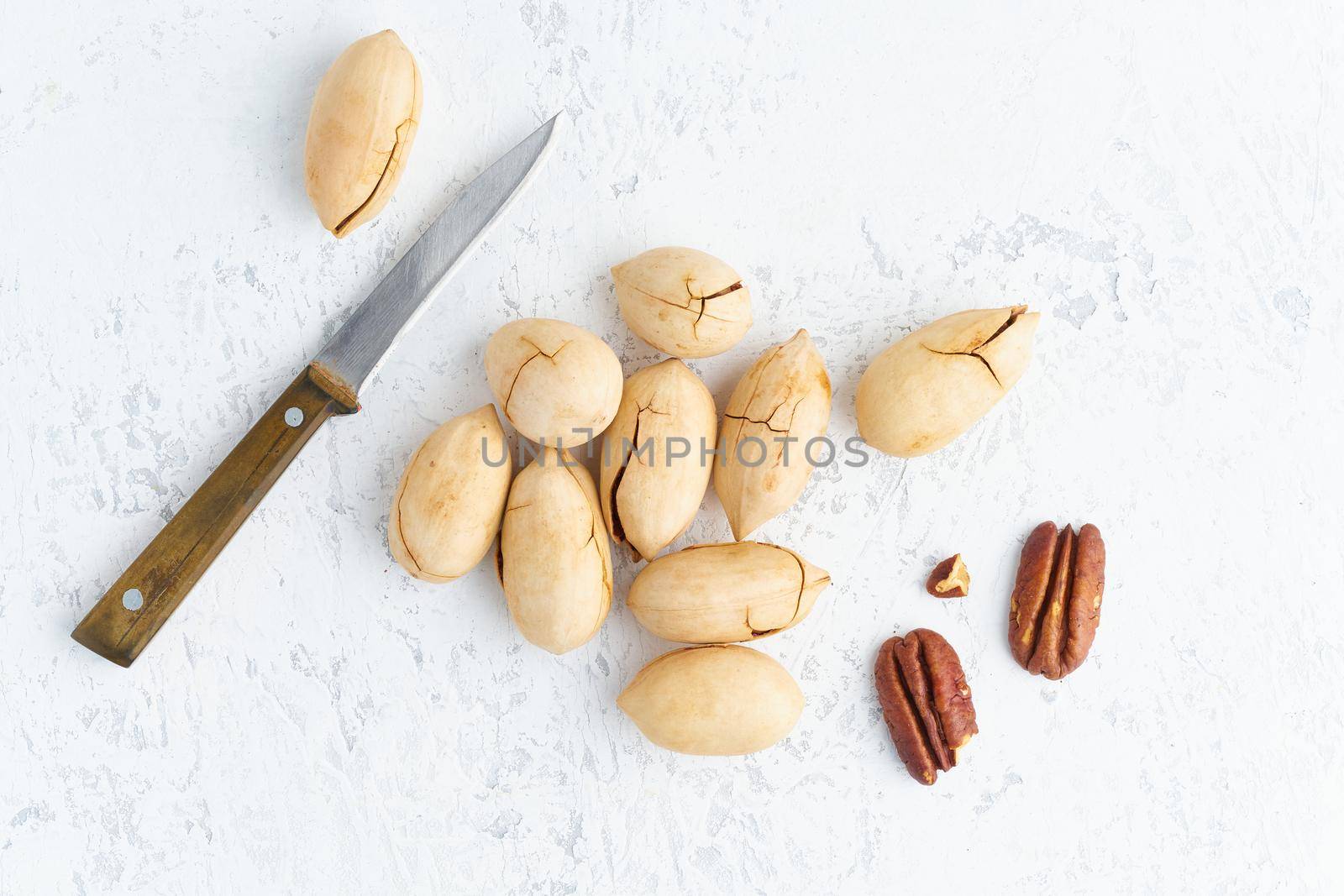 Top view open pecan and pecan in shell on a white stone background, overhead, copy space. Loose nuts on the table
