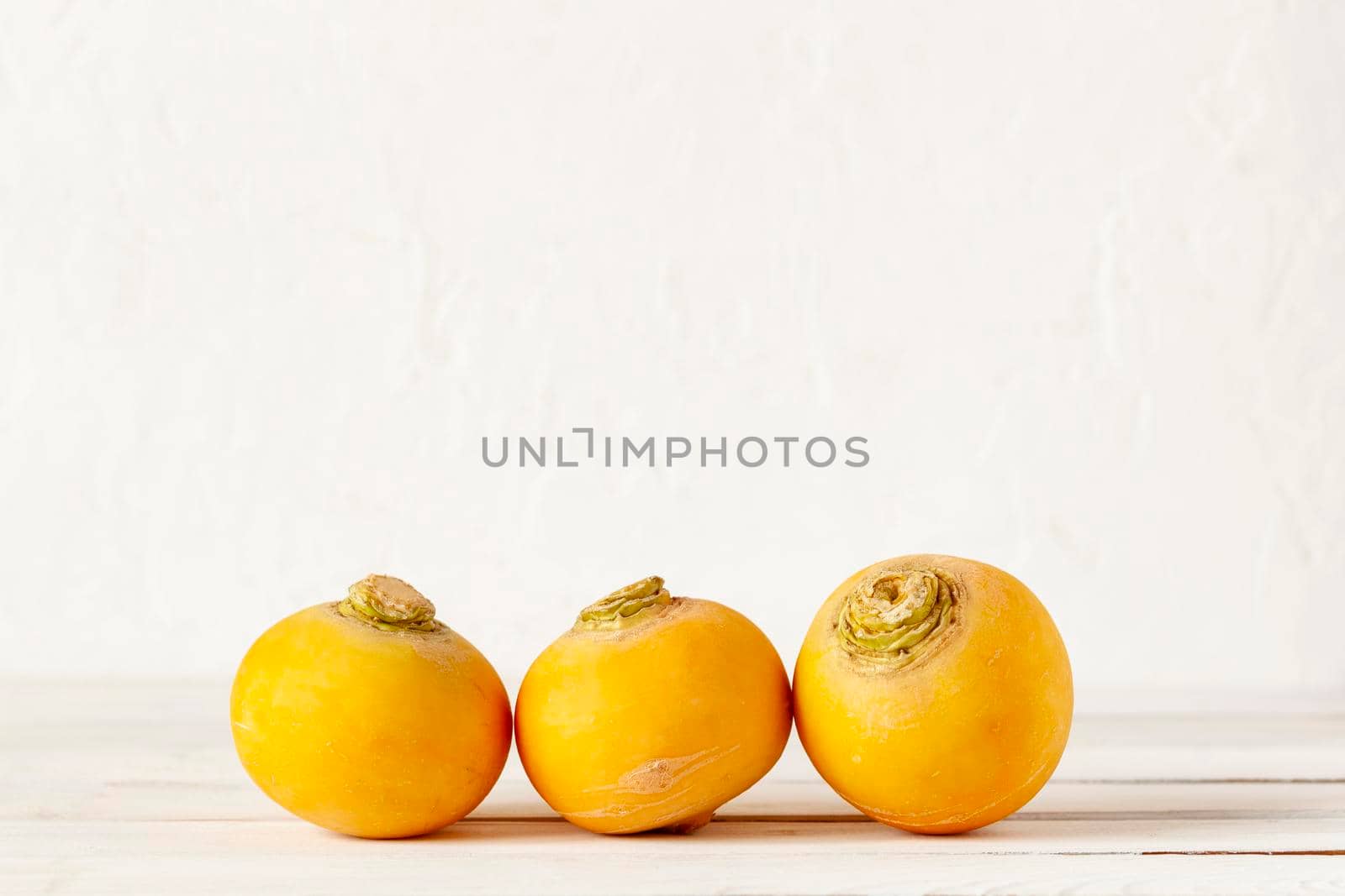 three yellow raw organic turnips on the wooden background, copy space