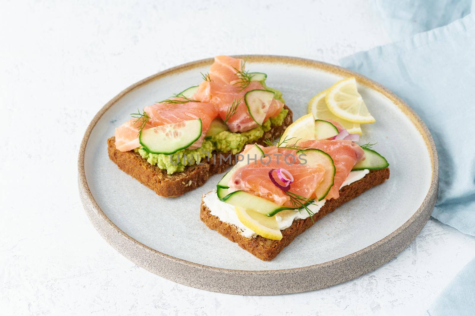 Smorrebrod - traditional Danish sandwiches. Black rye bread with salmon, cream cheese, cucumber, avocado on a wooden background