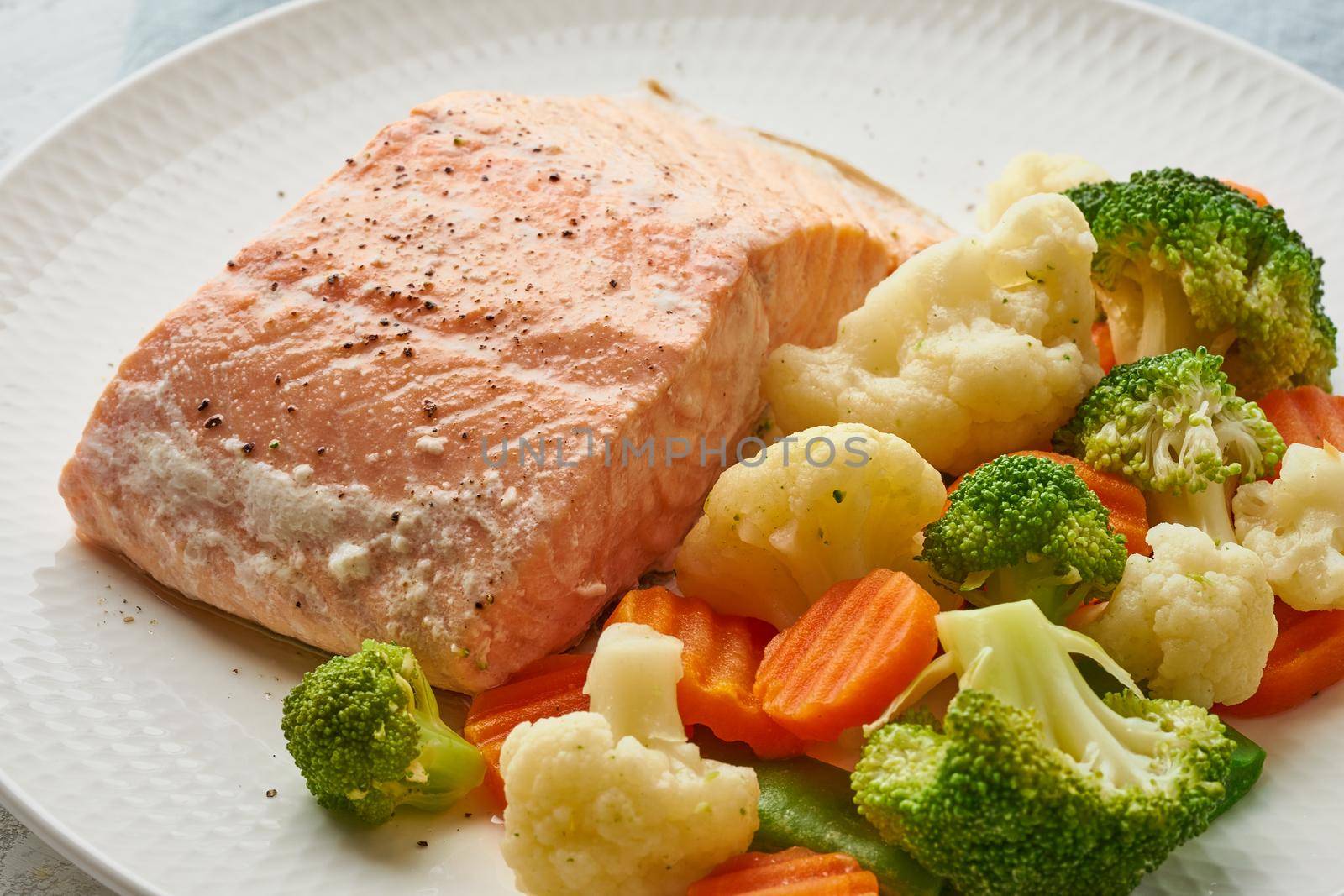 Steam salmon and vegetables, Paleo, keto, fodmap, dash diet. Mediterranean diet with steamed vegetables and fish. Healthy concept, white plate on a gray table, gluten free, lectine free, macro