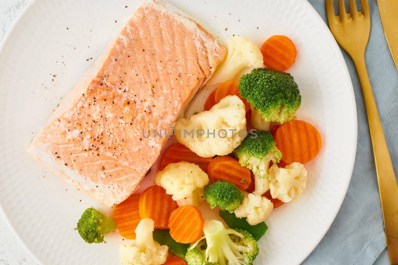 Steam salmon and vegetables, Paleo, keto, fodmap, dash diet. Mediterranean diet with steamed vegetables and fish. Healthy concept, white plate on a gray table, gluten free, lectine free, top view