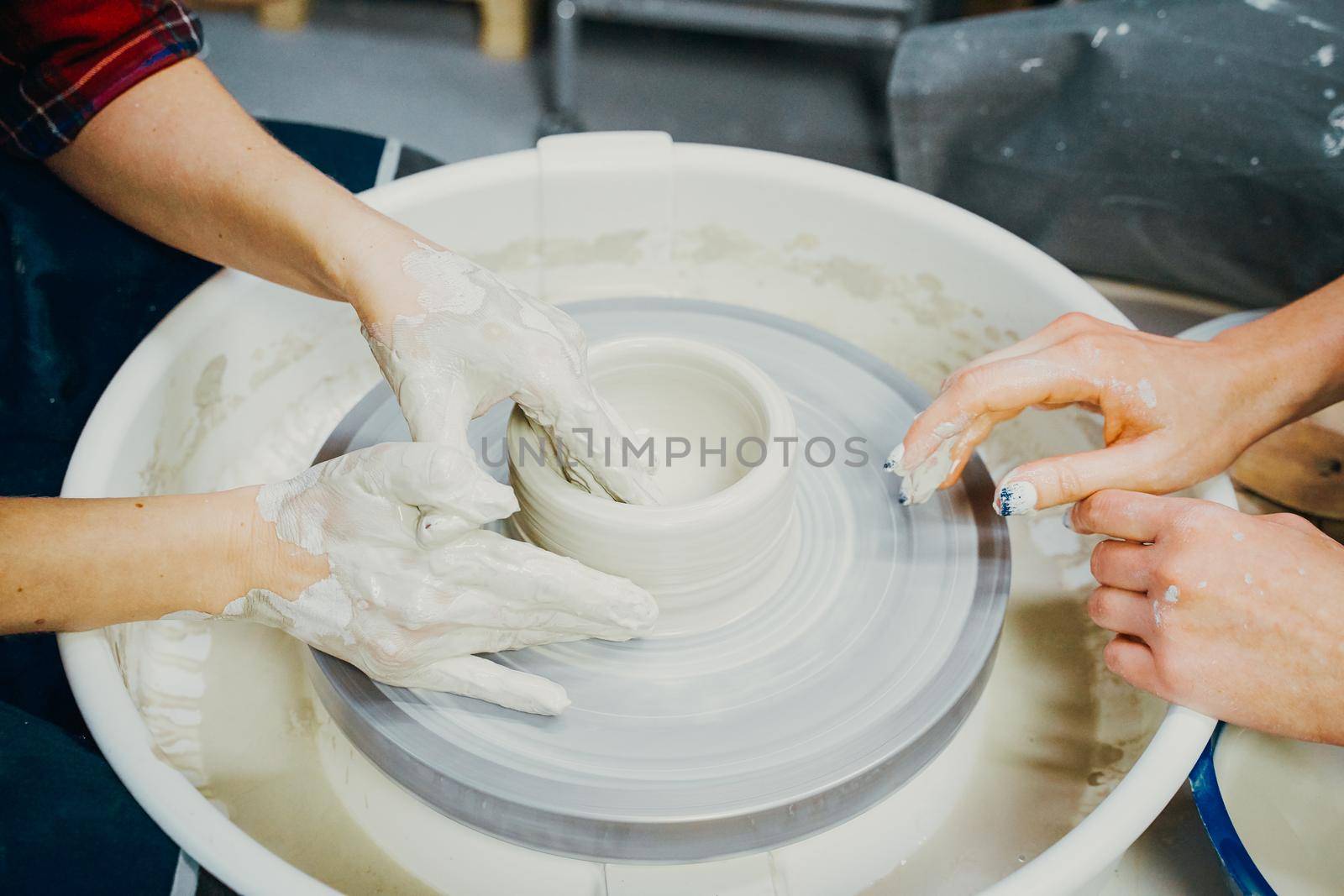 Woman making ceramic pottery, four hands close-up, focus on potters, palms with pottery by NataBene