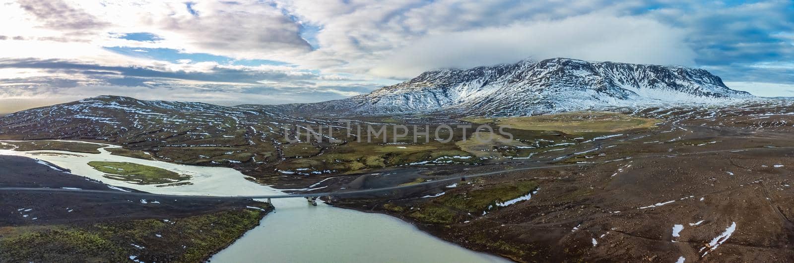 Huge panorama with bridge over the river and mountains with snow