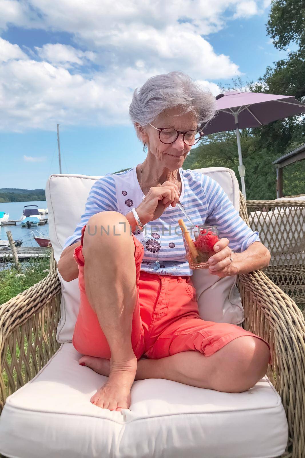 A gray-haired French woman sits in a cafe and eats ice cream lifestyle