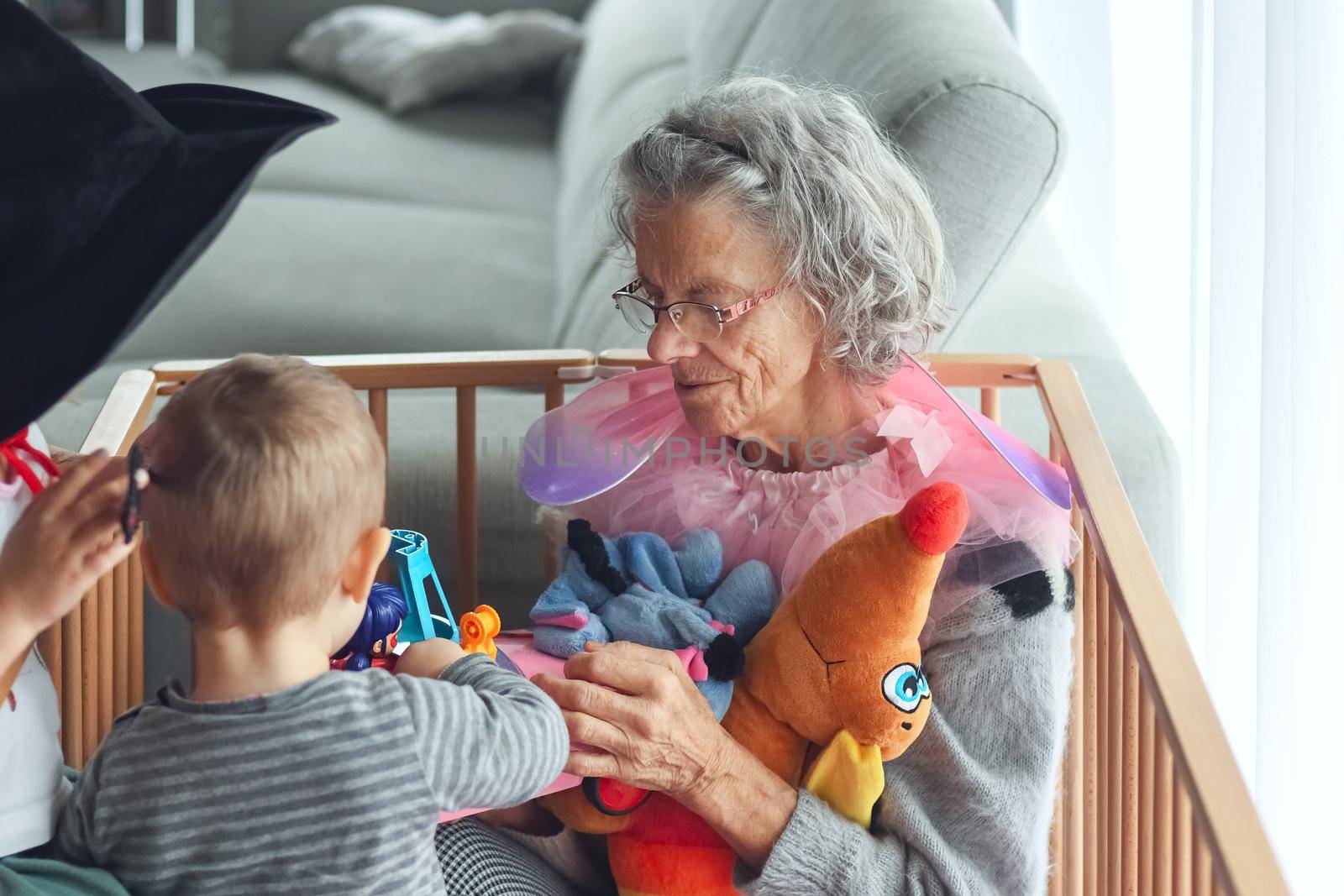 Gray-haired grandmother plays with her little grandchildren in a flat