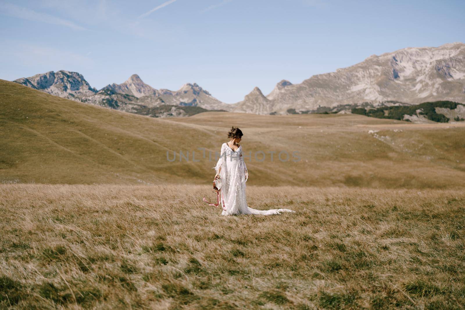 Girl in a white dress with a tambourine in her hands stands in a field. High quality photo
