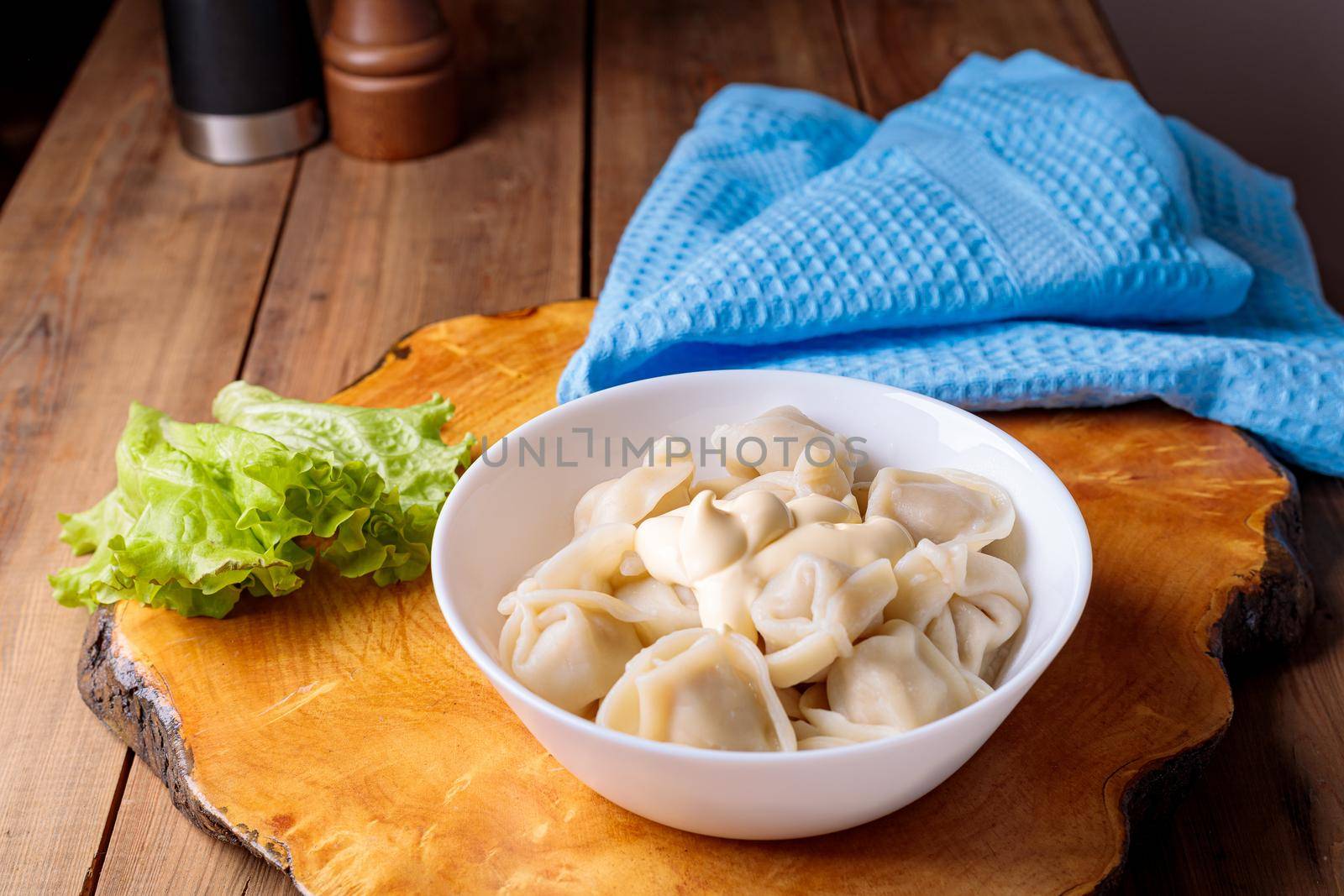 Dumplings in a white plate with salad on a wooden background. Russian national food.