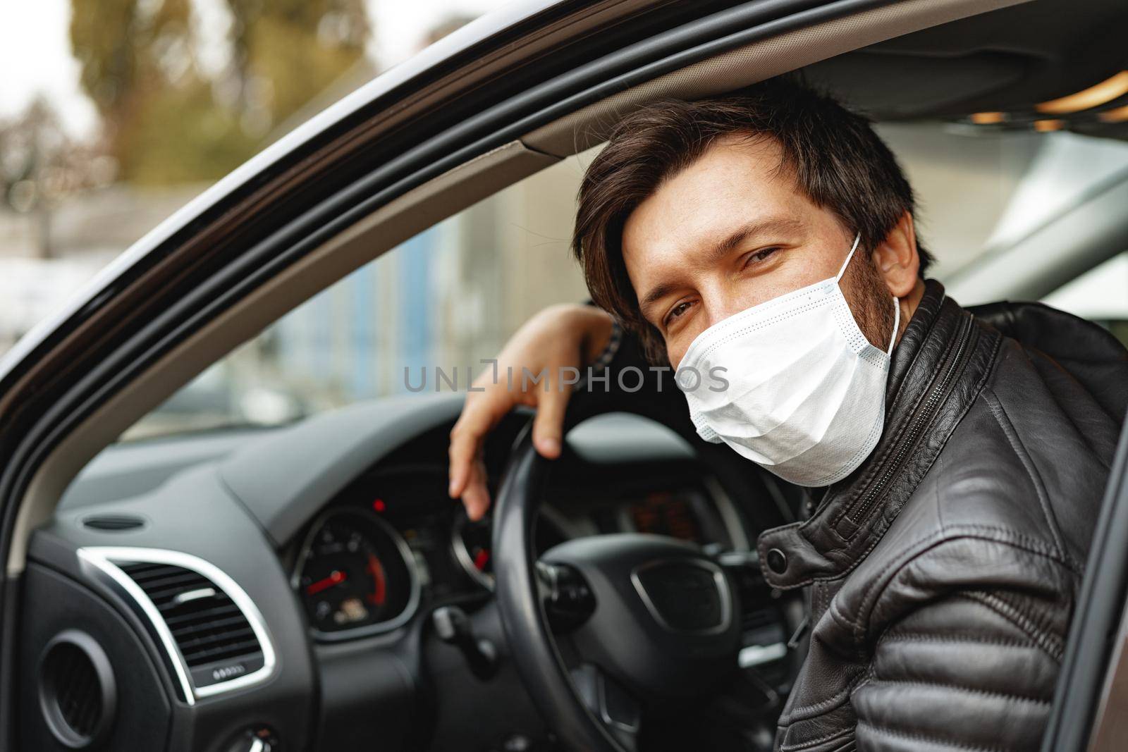 Young man driving car in medical mask, portrait