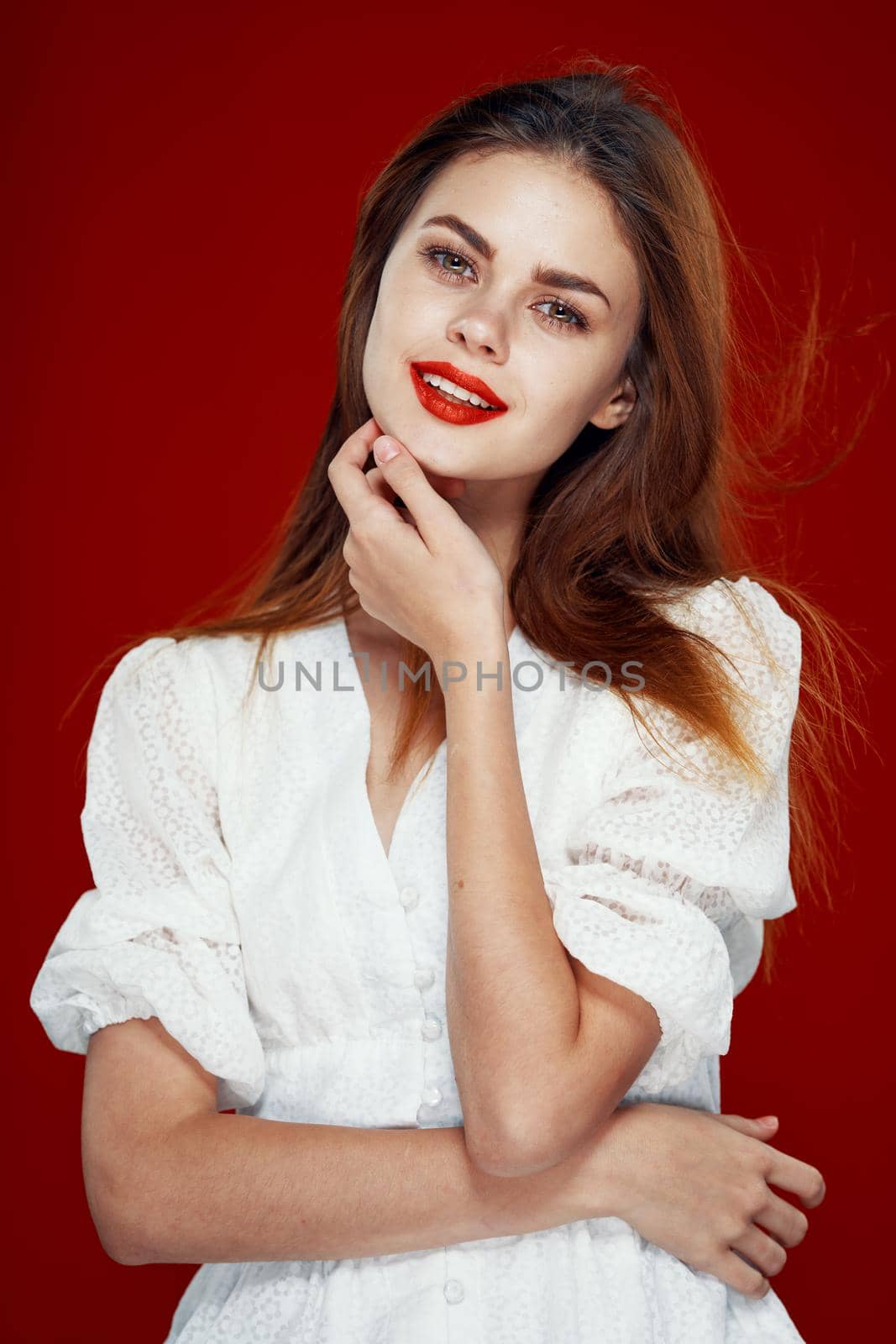 cheerful red-haired woman with red lips white dress red background. High quality photo