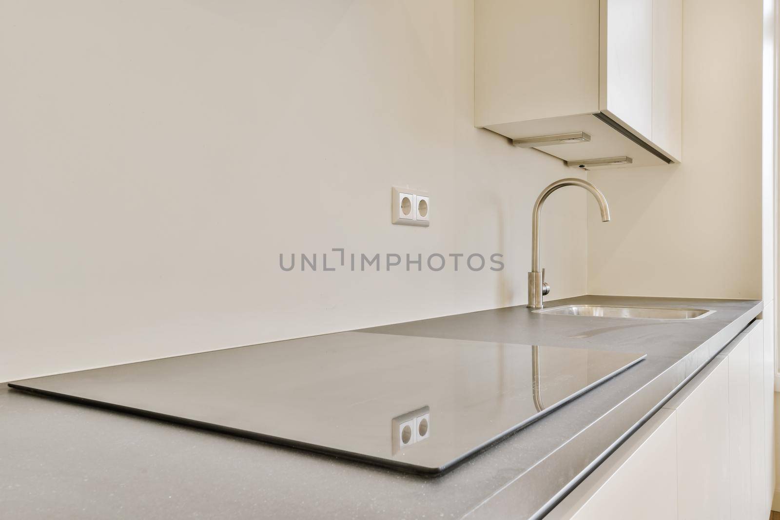 Stylish modern electric stove with sink in the background