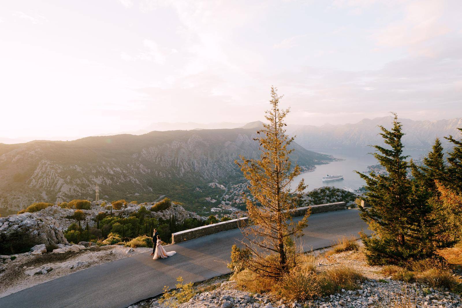 Bride and groom are walking along the road in the mountains against the backdrop of the bay. Drone by Nadtochiy