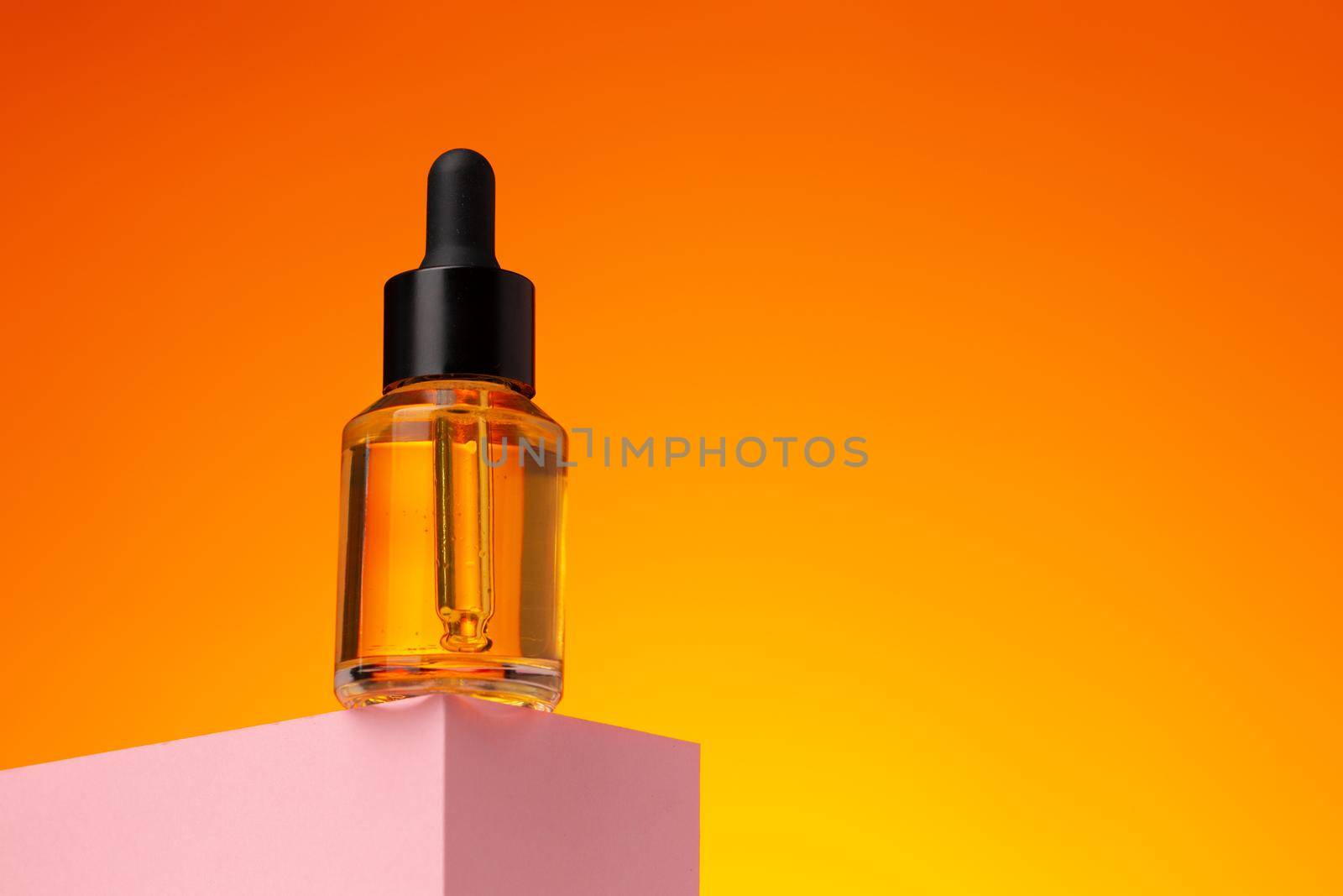 Beauty oil bottle with pipette against orange background close up