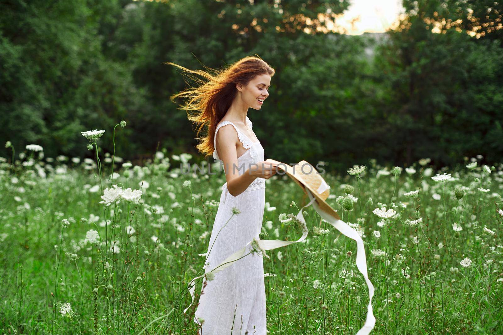 Woman in white dress hat holding flowers nature walk by Vichizh