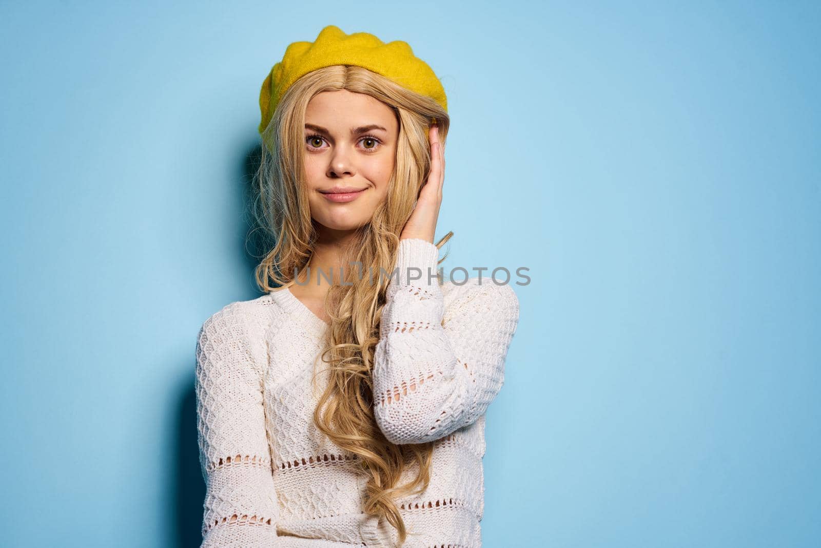 woman in yellow hat posing glamor blue background. High quality photo