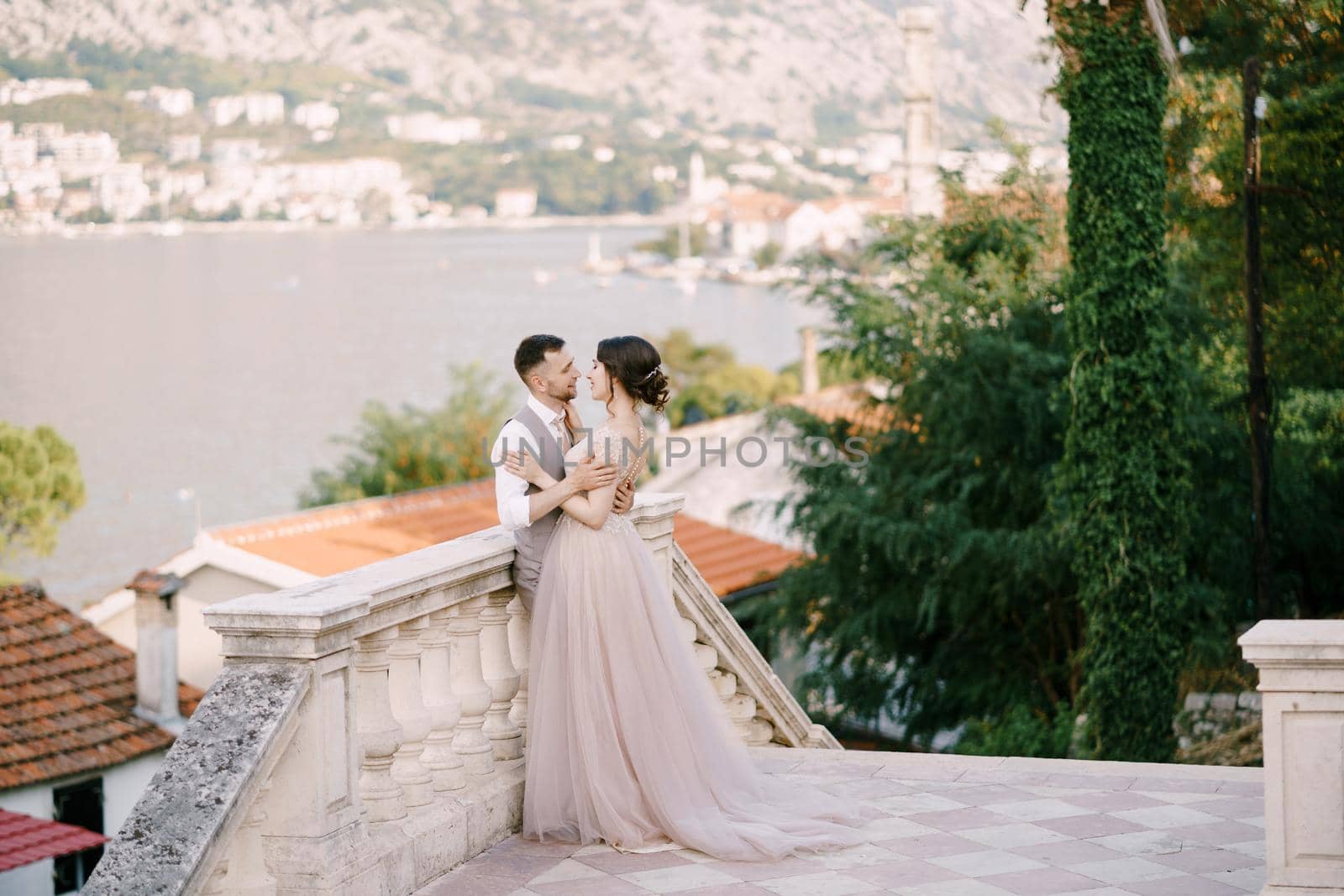 Groom hugs bride near the balustrade on the background of the bay. High quality photo