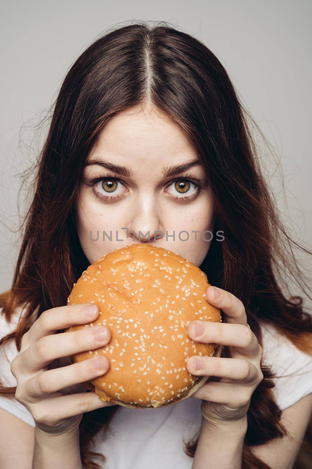 woman with a hamburger in her hands a snack fast food close-up by Vichizh