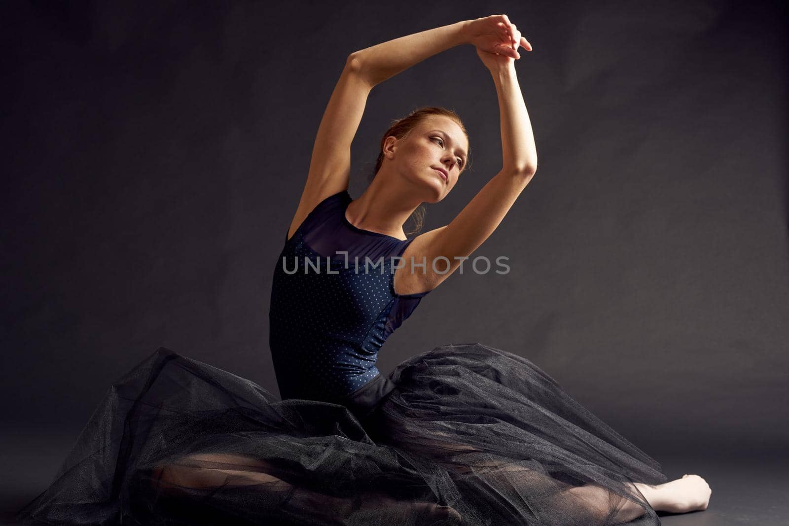 pretty woman in a black dress dance fashion exercise dark background. High quality photo