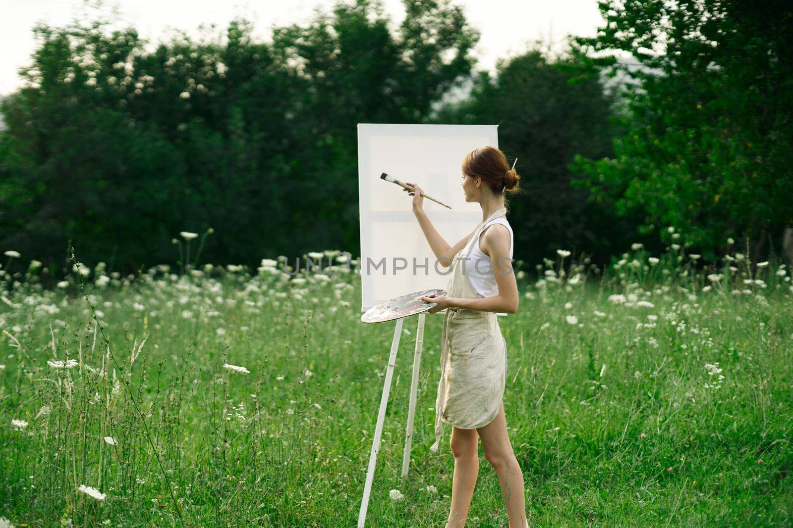 woman artist paints on easel in nature landscape by Vichizh