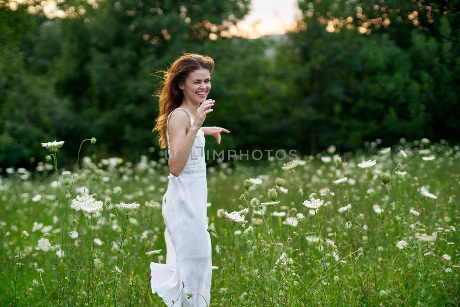 cheerful woman in a field with flowers in a white dress in nature by Vichizh