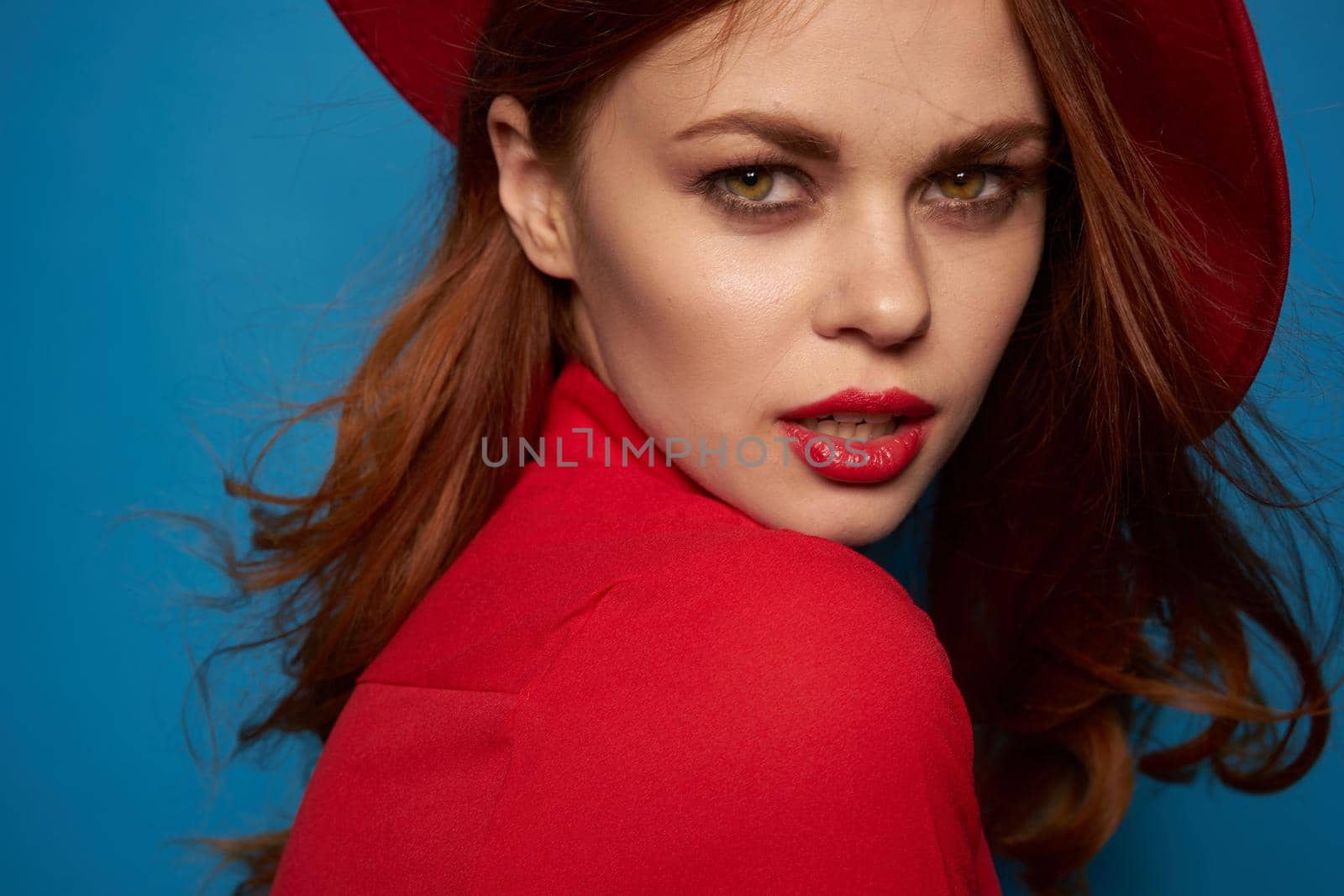 beautiful woman wearing a red hat cosmetics posing blue background. High quality photo