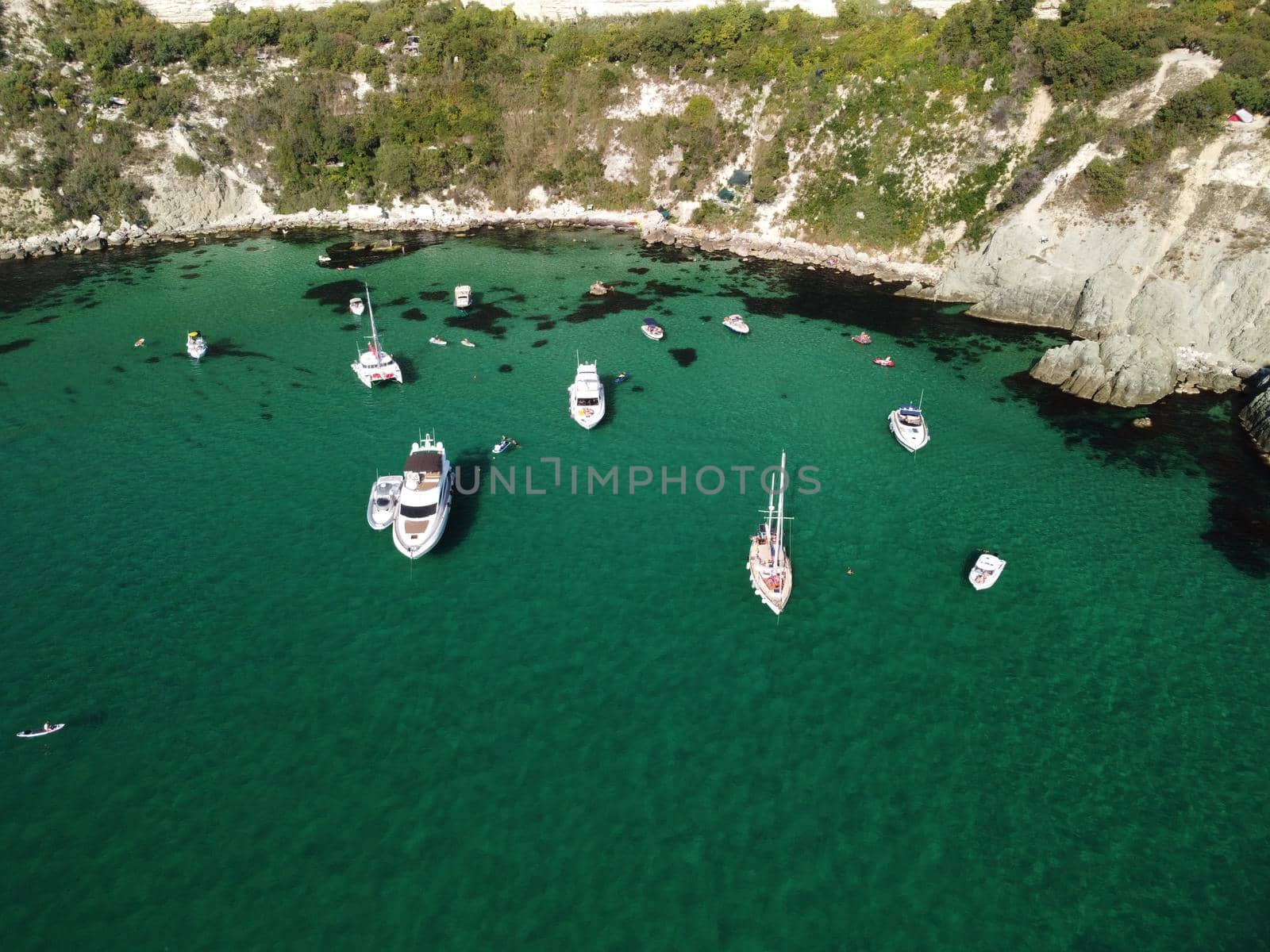 Sea landscape with rocky coastline on sunset time with cloudy sky. Yachts in the Sea on a background of rocky shores. The concept of perfect place for summer travel and rest.