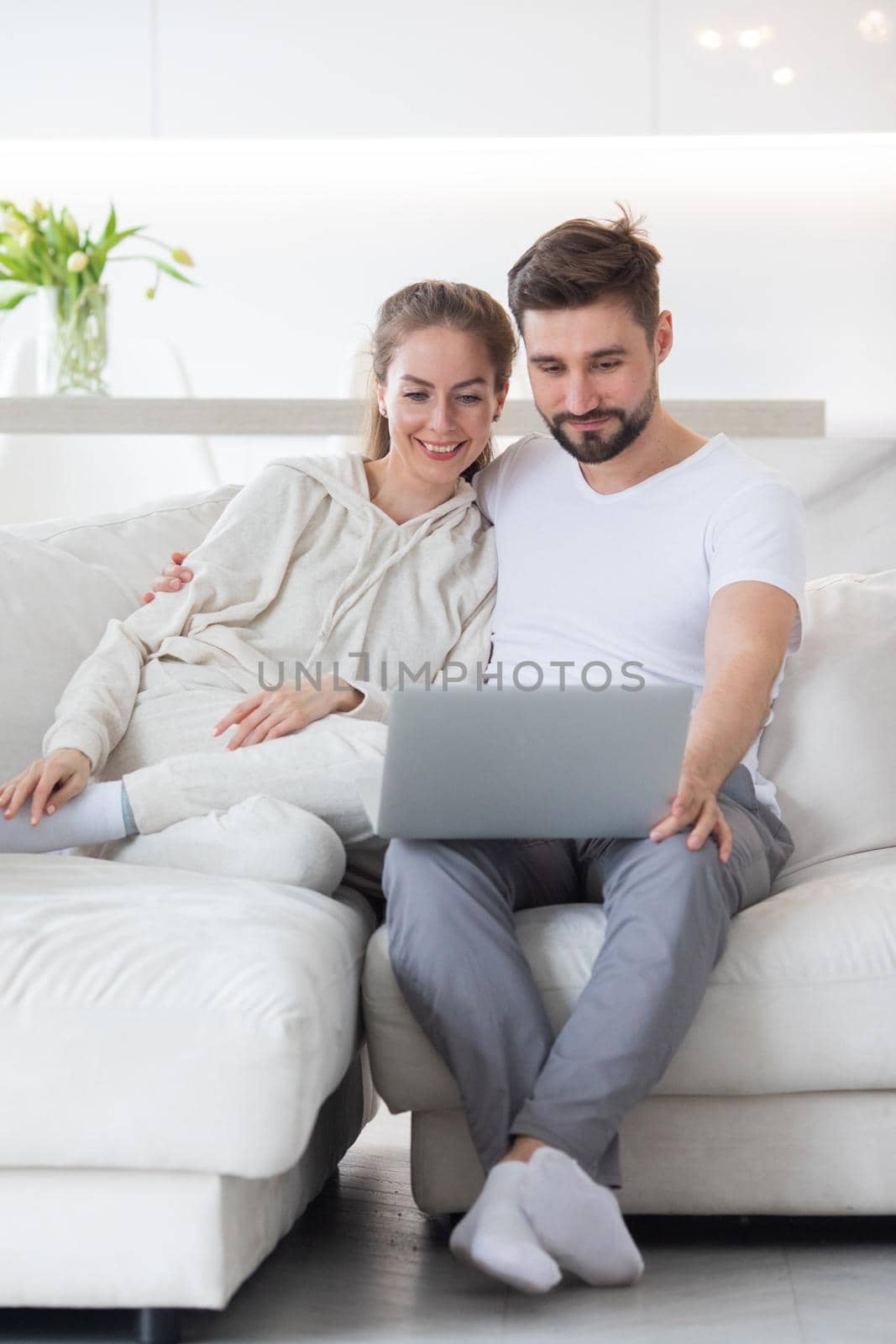 Portrait of mid adult couple relaxing in living room sitting together browsing internet on laptop computer