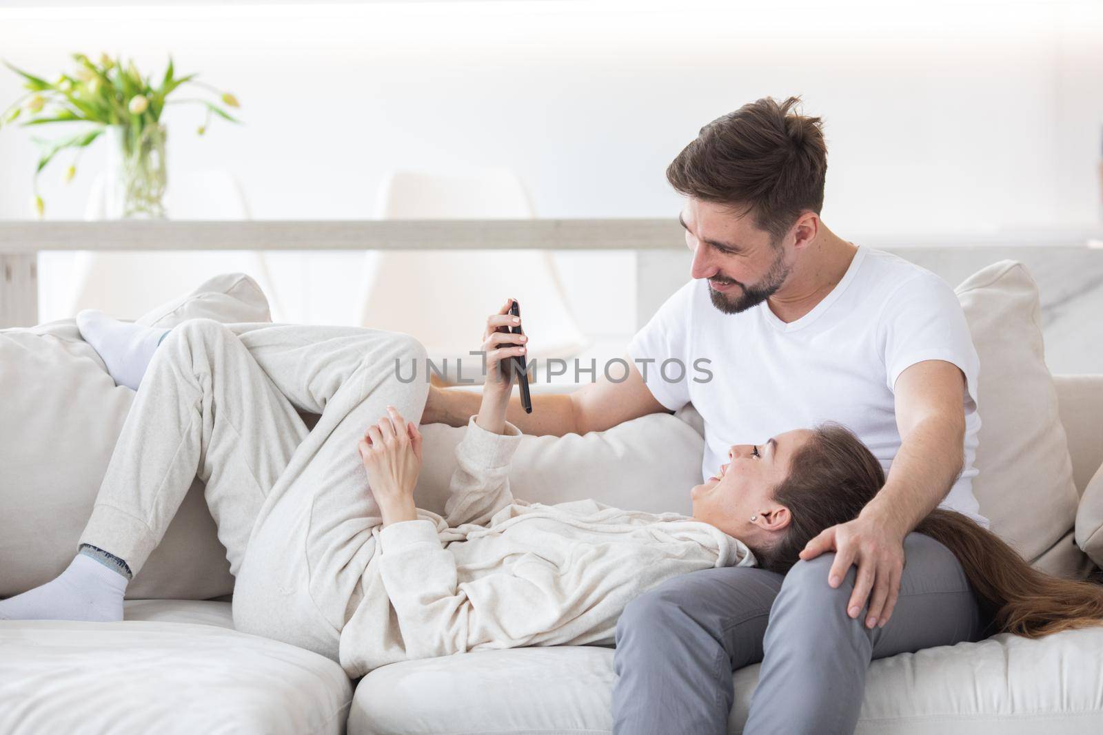 Couple relaxing in living room and smiling looking at smartphone