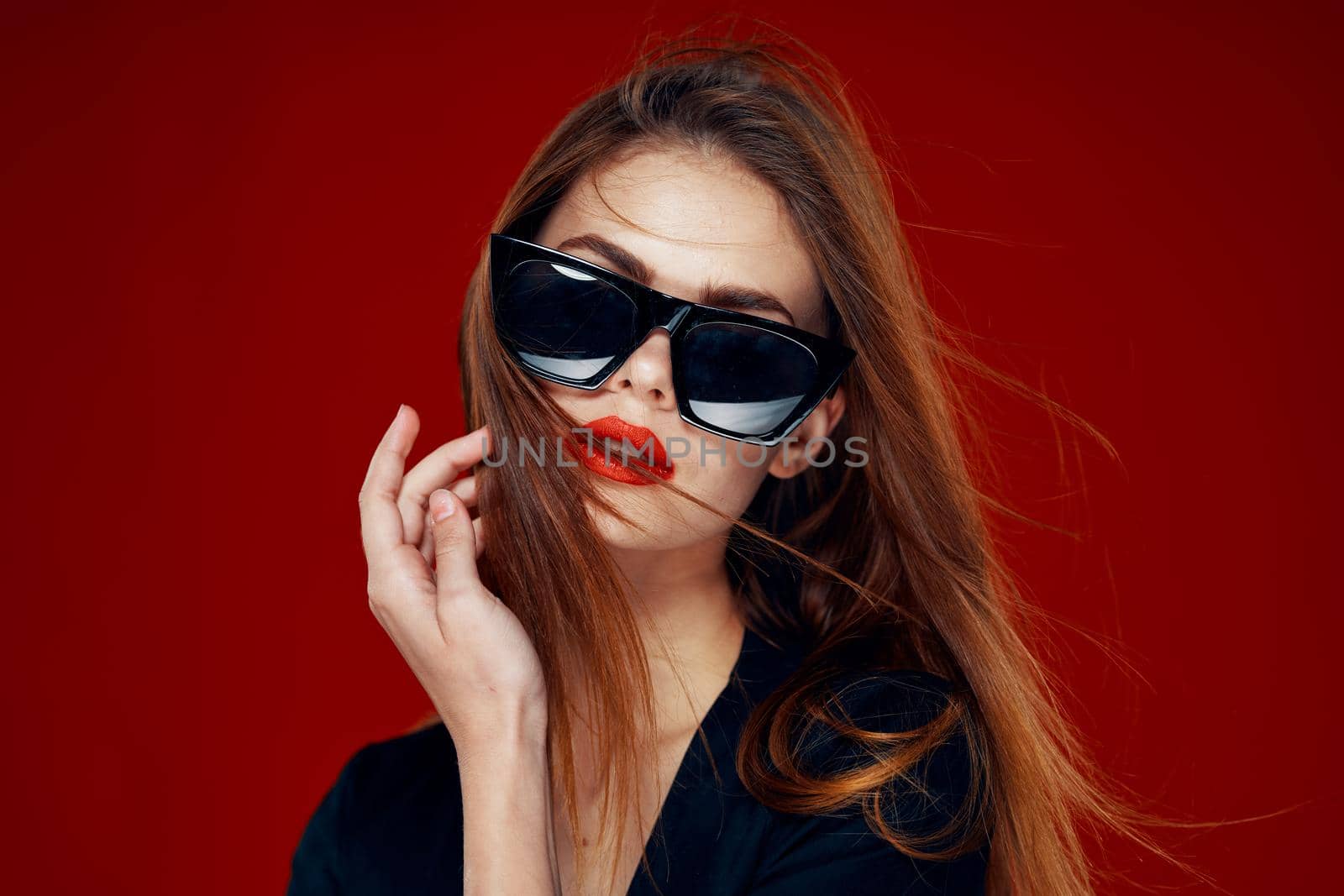 cheerful fashionable woman wearing sunglasses red lips posing red background by Vichizh