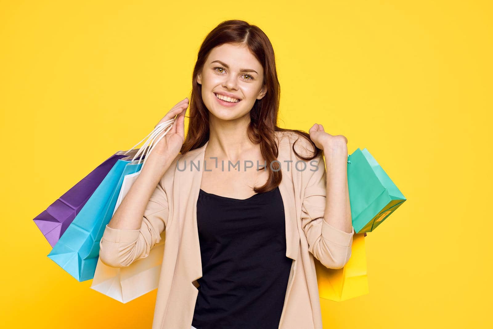 smiling woman with packages in hands Shopaholic yellow background. High quality photo