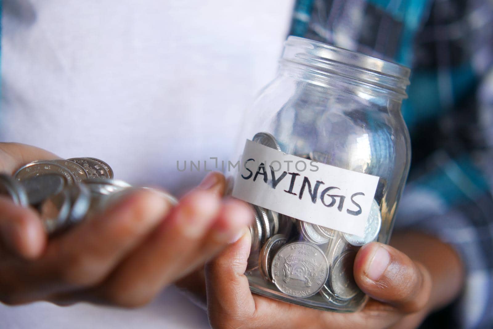 young man hand hold saving coins jar .