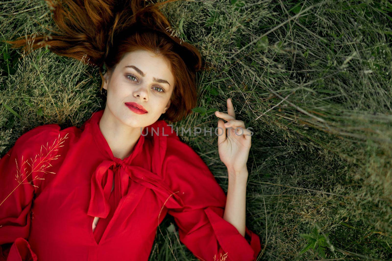 pretty woman in red dress lies on the grass landscape freedom. High quality photo
